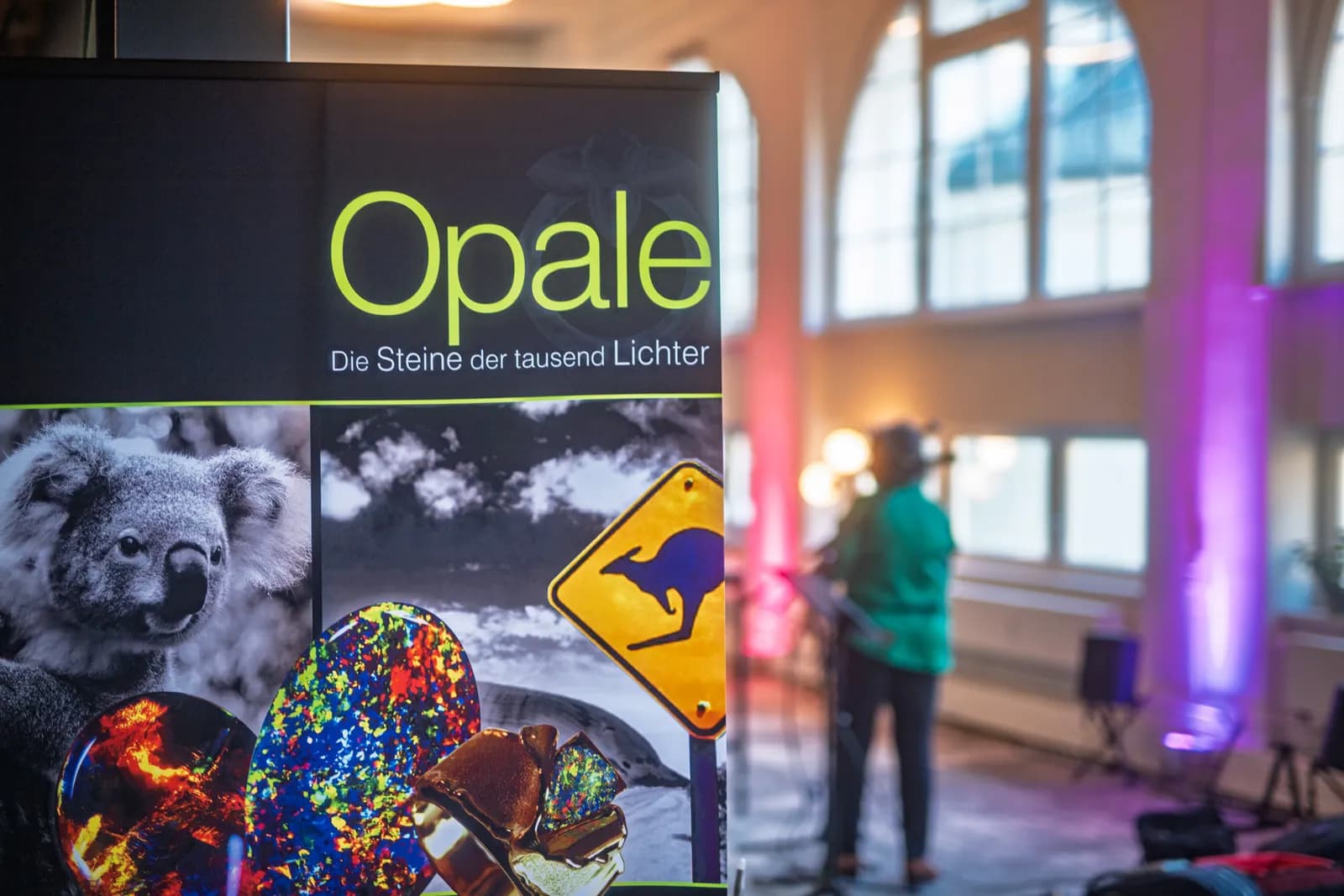 Banner „Opale – Die Steine der tausend Lichter“ im farbig beleuchteten Postwerk