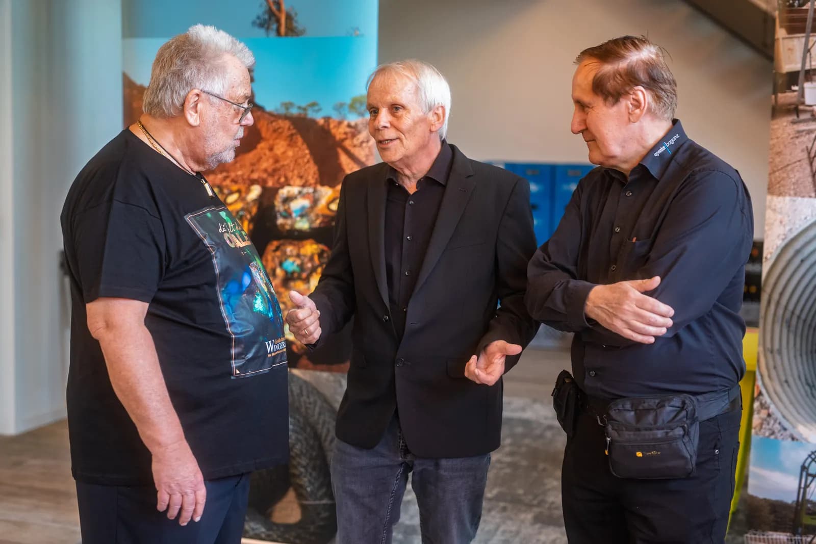 Drei Gäste im Gespräch zwischen den Ausstellungsfotos